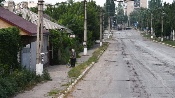 Житель подметает улицу у дома в Лисичанске