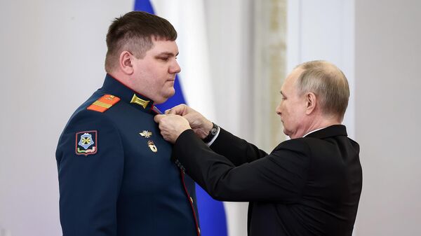Президент РФ Владимир Путин и сержант Юрий Мизерный (слева) на церемонии вручения медалей Золотая Звезда в Кремле накануне Дня Героев Отечества