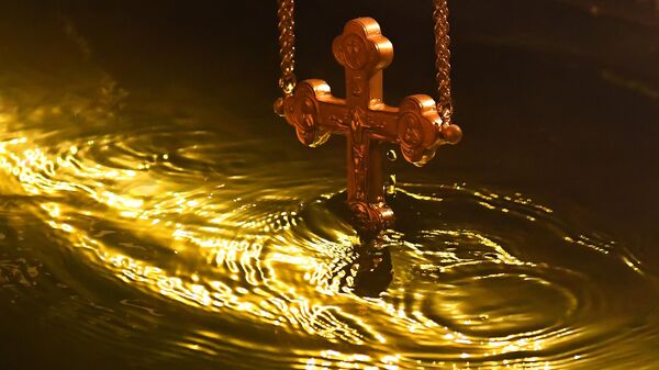 Православный священник совершает чин освящения воды по случаю праздника Крещения Господня в купели
