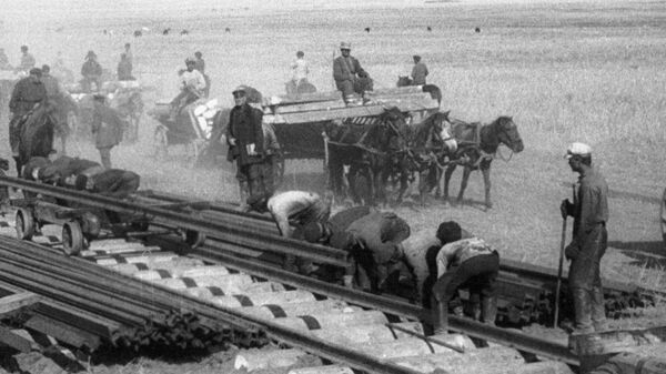 Рабочие укладывают рельсы на одном из участков строительства железной дороги