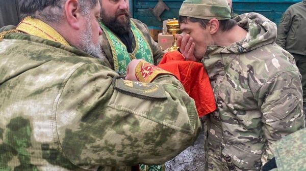 Отец Георгий (в центре снимка) причащает казаков на передовой