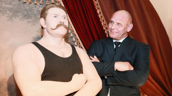 Борец классического (греко-римского) стиля, трёхкратный олимпийских чемпион, девятикратный чемпион мира, двенадцатикратный чемпион Европы, тринадцатикратный чемпион СССР,  Герой Российской Федерации Александр Карелин у фигуры легендарного русского атлета Ивана Поддубного в Государственном музее спорта.