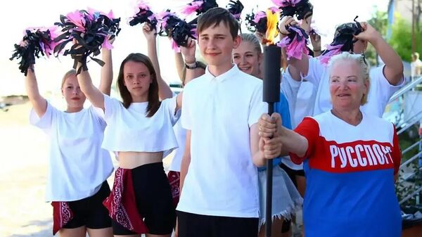 Участники эстафеты огня Олимпиады народов мира держат факел огня